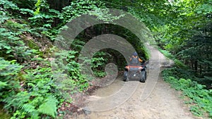 Mountains road with quad bikes on driving down the path in summer forest. ATVs vechicle on journey to the mountains