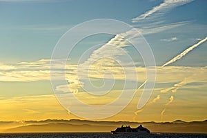 Mountains shrouded in mist in the distance as a cruise ship sails along the coast of Vancouver Island, Canada