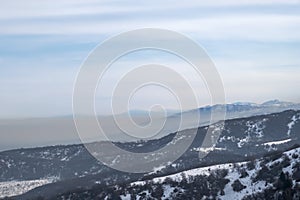 Mountains with smog rising from town. Visible border of clean and dirty air.