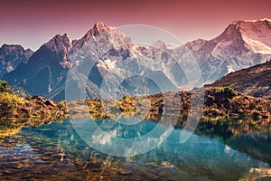 Mountains with snow covered peaks, red sky reflected in lake