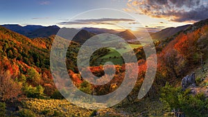 Mountains at sunset in Slovakia. Landscape with mountain hills orange trees and grass in fall, colorful sky with golden sunbeams.