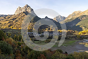 Mountainscape with a small town in the afternoon with foregorund of autumn  forest, Aragon