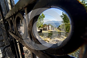 Mountainside Cemetary seen through the hole of an iron fence,central Montenegro,Eastern Europe