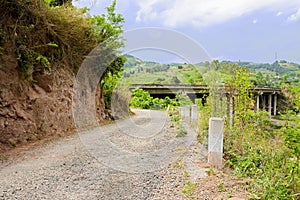 Mountainside country road before highway bridge in sunny spring