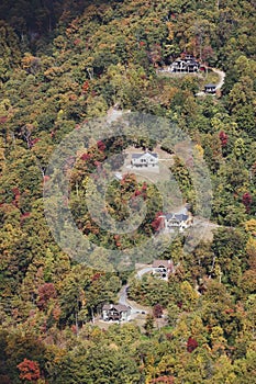 Mountainside houses along winding road surrounded by fall trees