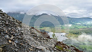 On mountainside by slate looking to valley in low cloud