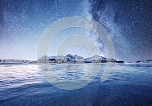 Mountans and reflection on the water surface at the night time. Sea bay and mountains at the night time. Milky way above mountains