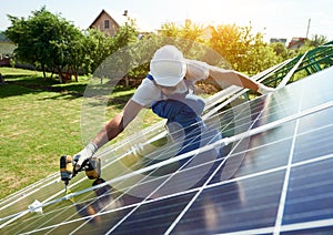 Mounter installing solar panels for renewable energy on house`s roof.