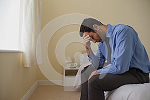 Mournful man sitting head in hands on his bed