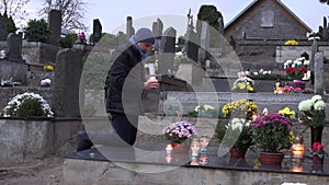 Mourning man kneel on grave at cemetery and pray with burn candle in hands. 4K