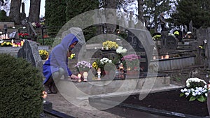 Mourning woman sit on grave at cemetery and pray with burn candle in hands. 4K