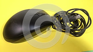 A Mouse computer USB cable with black color in the room with Yellow Background