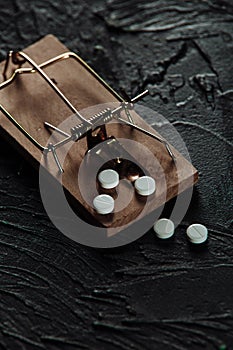 Mousetrap with a bait in the form of pills. Addiction and dependence on drugs. Vertical image