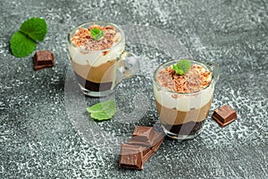 Mousse Three chocolates in a glass decorated with mint on a dark background. Layered delicious dessert. place for text, top view