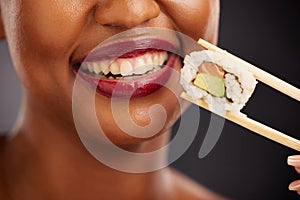 Mouth, eating and woman with sushi and chopsticks in studio for healthy food or teeth. Black female model with makeup on