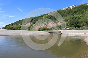 The mouth of the river Axe as it meets the sea at Axmouth in Devon. It is quite narrow and becomes a raging torrent when the tide