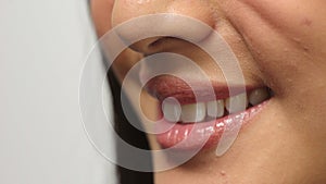 Mouth of a shy woman with acne giving a nervous or unsure smile, feeling anxious and uncomfortable in studio. Closeup of
