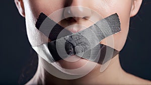 The mouth, taped shut, symbolizes the suppression of free speech. This stark representation highlights the struggle for self- photo