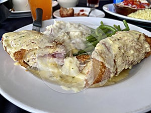 A mouth watering meal of chicken  cordon bleu with mashed potatoes and green beans