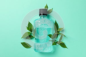 Mouthwash and leaves on mint background