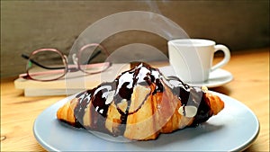 Mouthwatering Chocolate Croissant with a Cup of Steaming Hot Coffee in the Backdrop