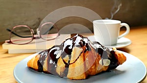 Mouthwatering Chocolate Croissant with a Cup of Steaming Hot Coffee in the Backdrop