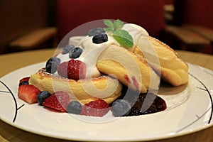 Mouthwatering Fluffy Souffle Pancake with Fresh Whipped Cream and Mix Berries Served on white Plate
