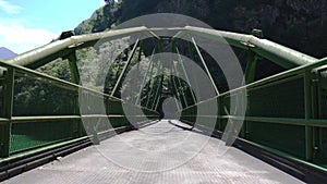 Movement along a green metal bridge over the river in the mountains