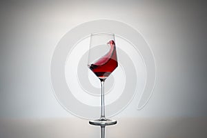 movement of a crystal glass full of red wine. red wine glass isolated on grey background with reflection on the base and