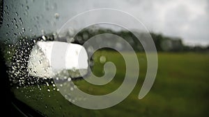 Movement of rain falling on car windshield, drive car on street in city at heavy rain storm, blurred traffic light.