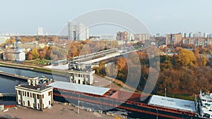 The movement of ships and barges along the canal through the river gateway in autumn sunny day.