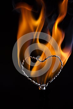 The movement of the smoke and flame rising on a heart shape on a black background