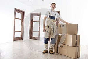 Mover with cardboard boxes in new apartment. Relocation services worker in indoor house. Loader in uniform with box