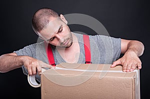 Mover guy packing carefully box with duct tape