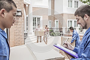 Mover holding clipboard and invoice, family in the background