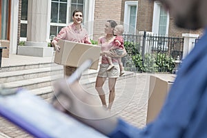 Mover holding clipboard and invoice, family in the background