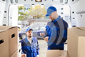 Mover Looking At His Partner Writing On Clipboard photo