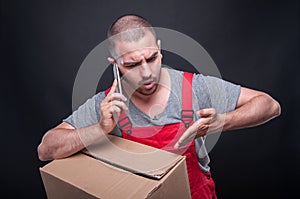 Mover man holding box looking confused on phone