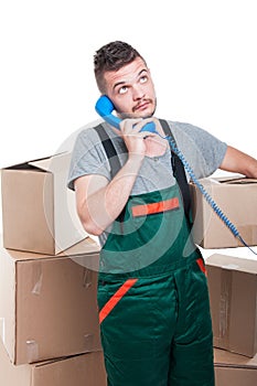 Mover man holding cardboard box talking at telephone