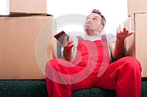 Mover man sitting on couch holding phone and gesturing