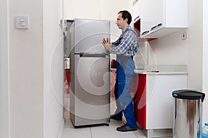 Mover Placing Refrigerator In Kitchen