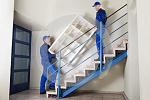 Movers Carrying Shelf While Climbing Steps