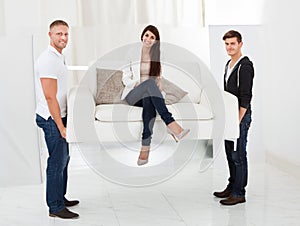 Movers carrying sofa with client