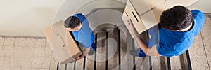 Movers Team Carrying Boxes Down Stairs