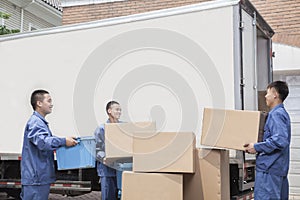 Movers unloading a moving van, many stacked cardboard boxes