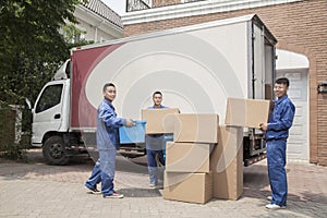 Movers unloading a moving van, many stacked cardboard boxes