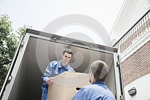 Movers unloading a moving van, passing a cardboard box