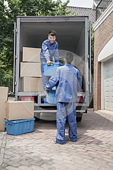 Movers unloading a moving van, passing a cardboard box