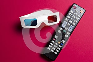 Movie on 3d TV. Watch movies concept. 3d glasses and remote control from the TV on pink background.