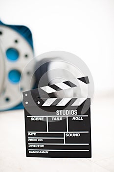 Movie clapper board closeup with movie reels in background
